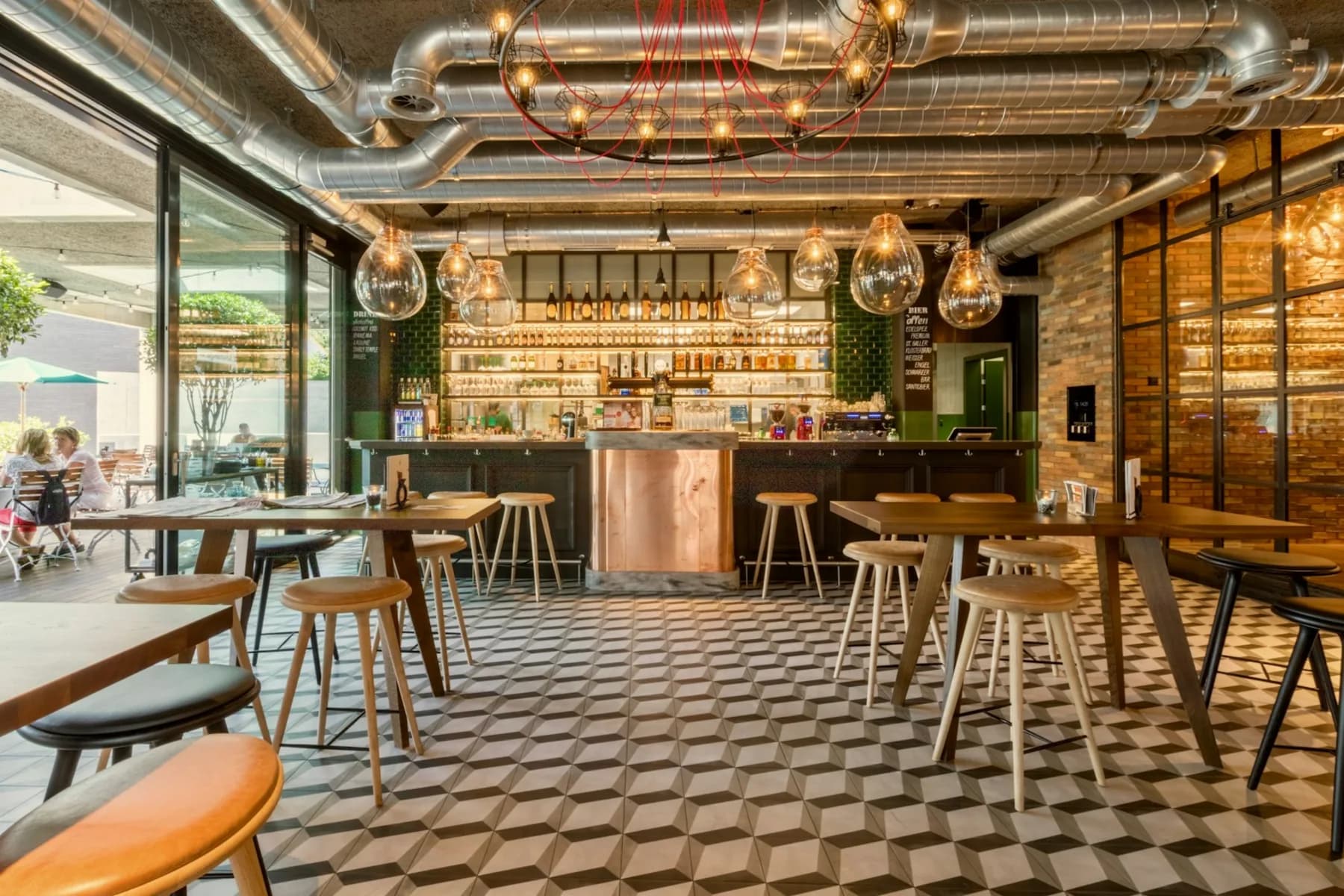 Empty bar and restaurant interior with wooden bar stools, a patterned tile floor and glass pendant lamps