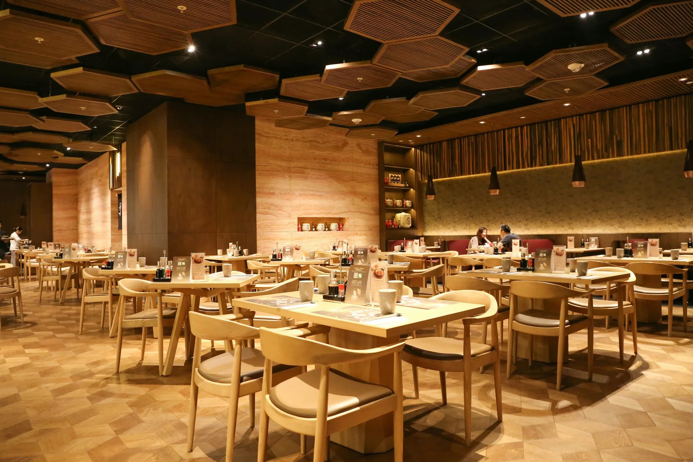 An empty dining room before service, wooden tables and chairs under a warm timber ceiling